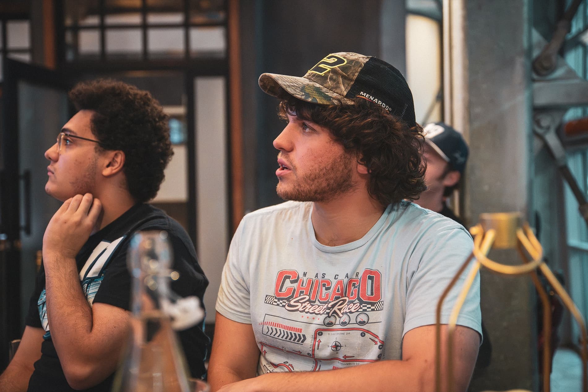 Two young men at a table watch the race, one in a Chicago Street Race T-shirt.